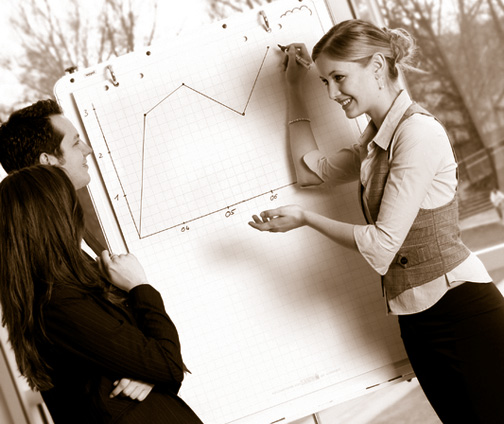 Eine Trainerin erklärt zwei Kollegen ein Chart.